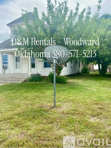 A sign for D&M Rentals in Woodward Oklahoma is displayed in front of a house.