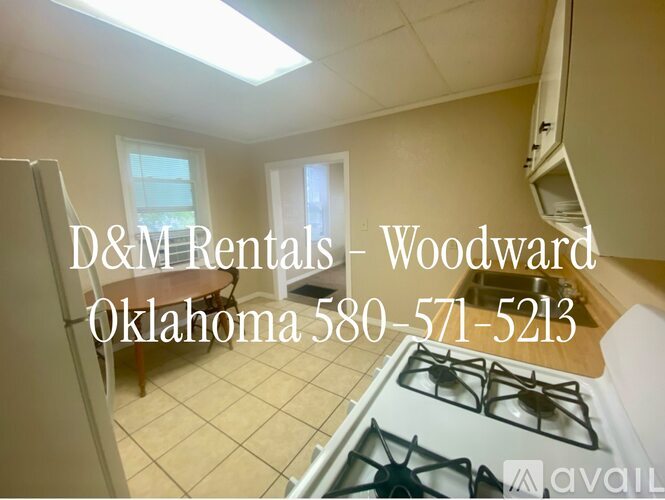 A kitchen with a stove top and a sign for D&M Rentals in Woodward Oklahoma.