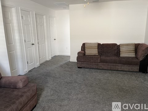 A living room with a brown couch and a grey carpet.