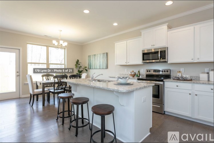 A kitchen with white cabinets and a center island with bar stools.
