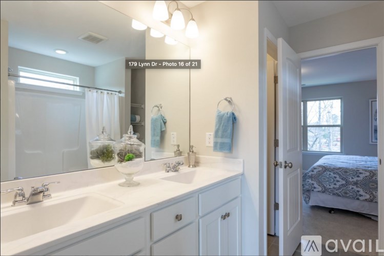 A bathroom with a white sink and mirror, a bedroom with a bed and a window, and a hallway with a door.