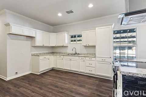 A kitchen with white cabinets and a marble countertop.