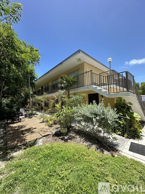 A house with a balcony and a garden in front.
