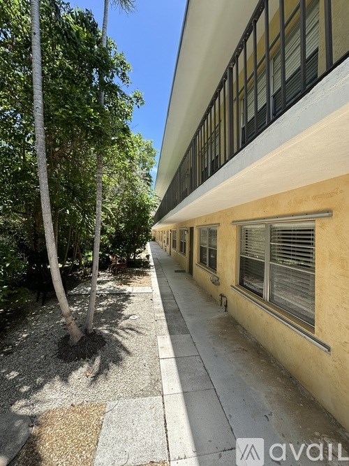 A long building with windows and a tree in front.