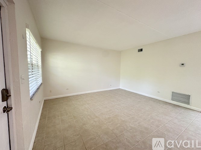 A room with a tiled floor and a window with blinds.