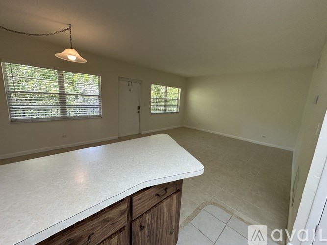 A room with a white countertop and wooden cabinets.
