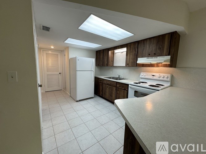 A kitchen with white appliances and a skylight.