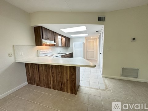 A kitchen with a white countertop and wooden cabinets.