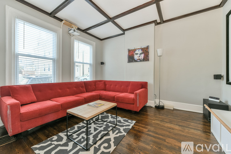 A red couch sits in a room with wooden floors and a zebra print rug.