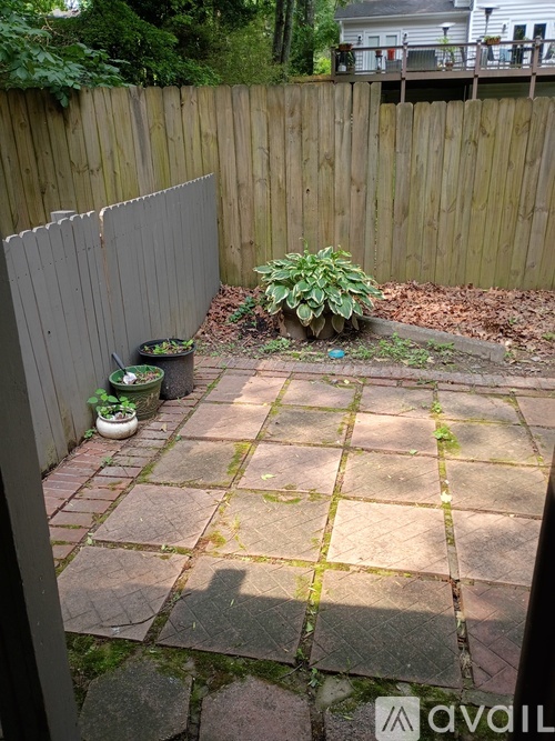A backyard with a stone patio and a wooden fence.