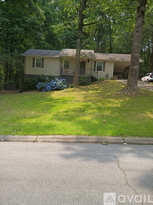 A house with a green lawn and trees in the background.