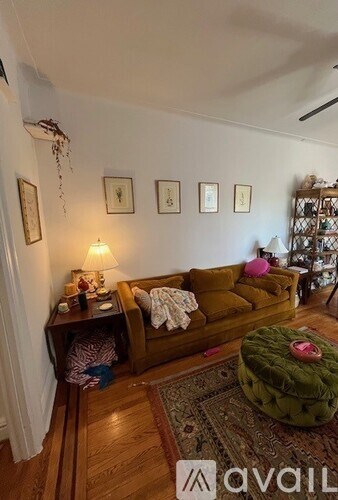 A living room with a brown couch, a green ottoman, and a rug on the floor.