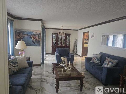 A living room with a blue couch, a wooden coffee table, and a painting on the wall.
