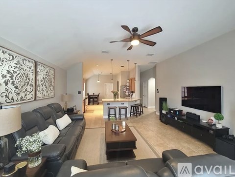 A living room with a black couch and a ceiling fan.