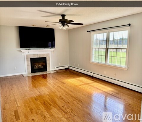 A living room with a fireplace and a television mounted above it.