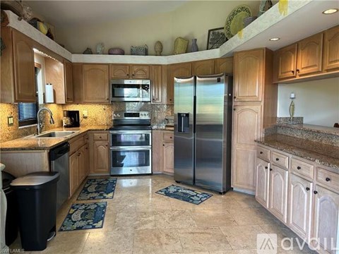 A kitchen with wooden cabinets and a marble floor.