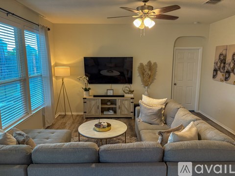 A living room with a grey couch and a television on a stand.