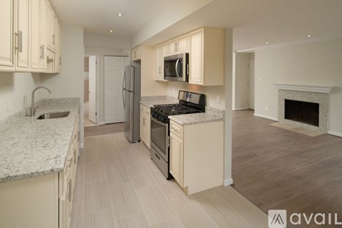 A kitchen with a granite countertop and a fireplace in the living room.