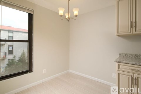 A room with a window, a chandelier, and a cabinet.