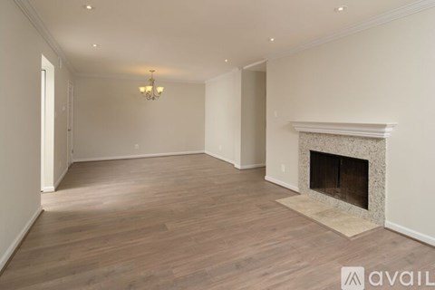 A spacious room with a fireplace and wooden flooring.