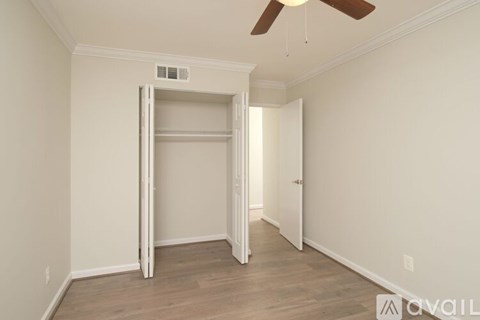 A room with a white door and a ceiling fan.