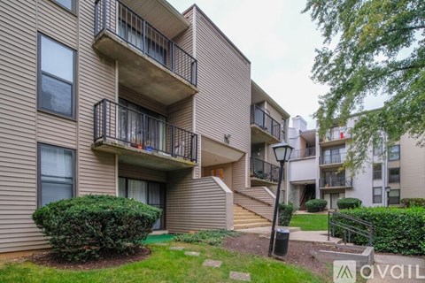 A building with a balcony and a green bush in front.