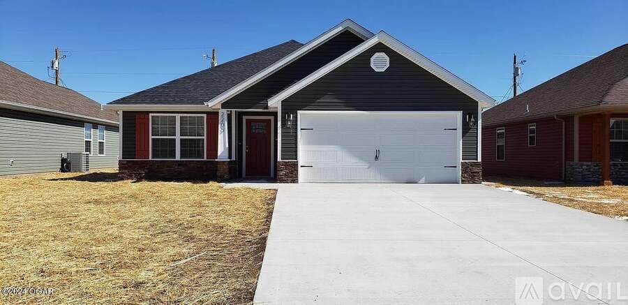 A two-car garage with a red door is in the foreground.