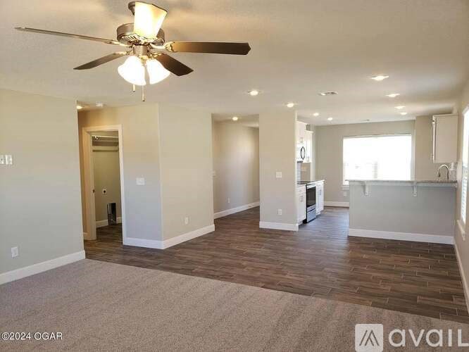 A spacious living room with a ceiling fan and hardwood flooring.
