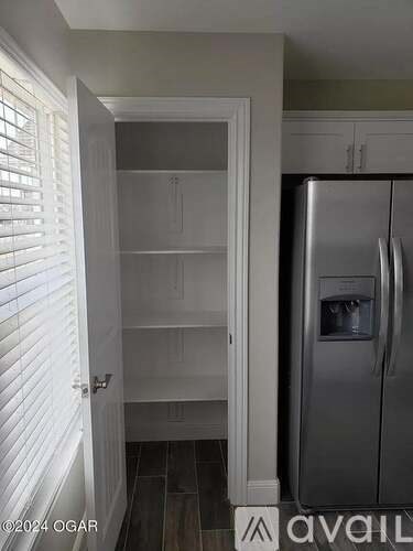 A kitchen with a refrigerator and an open door.
