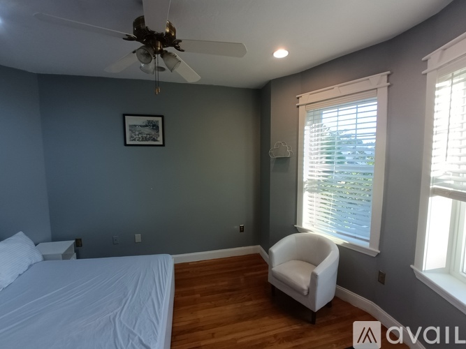 A bedroom with a bed, chair, and window.