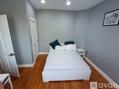 A bedroom with a white bed and wooden floors.