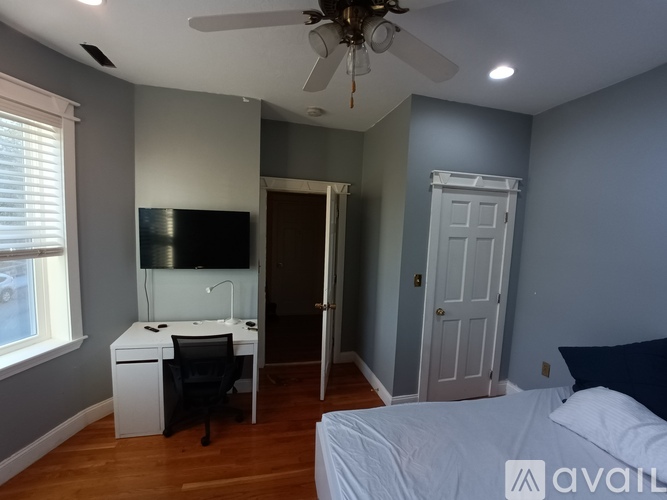 A room with a bed, desk, and television.