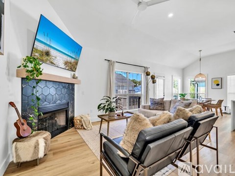 A living room with a fireplace, a guitar, and a painting of a beach scene.