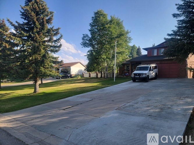 A driveway leads to a house with a white van parked in front.
