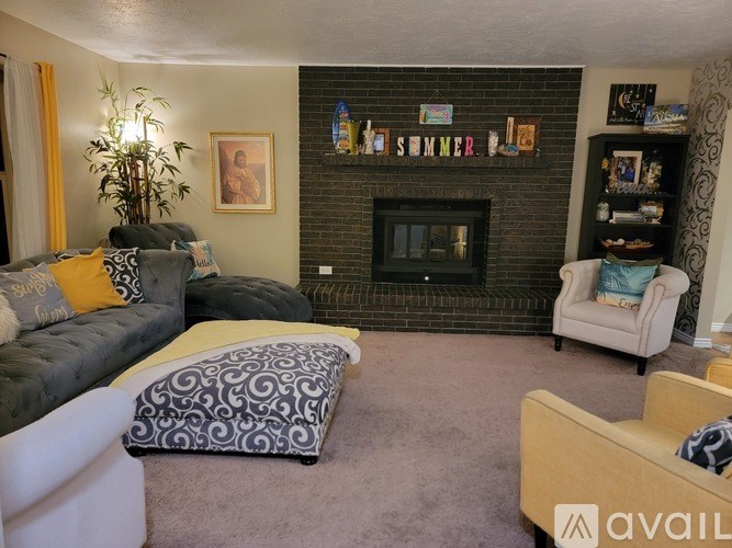 A living room with a grey couch, a black and white patterned pillow, a fireplace, and a wall with the word "SUMMER" written on it.