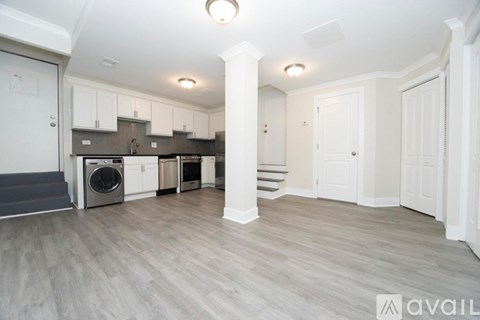 A kitchen with white cabinets and a grey floor.