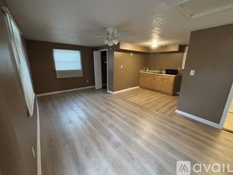 A spacious room with wooden flooring and a ceiling fan.