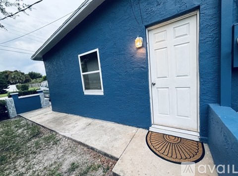 A blue house with a white door and a brown doormat.