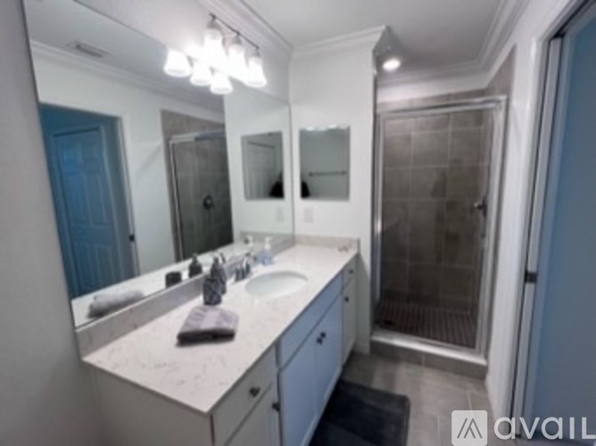 A bathroom with a sink, mirror, and shower.