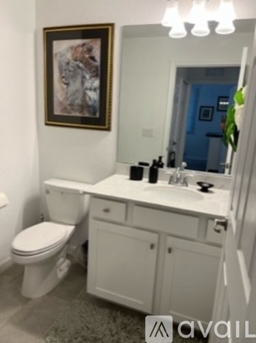 A bathroom with a toilet, sink and a painting on the wall.