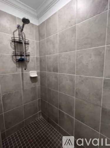 A tiled shower with a glass door and a shower head.