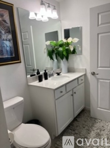 A white bathroom with a toilet, sink, and mirror.