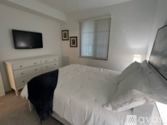 A bedroom with a bed, dresser, and a television.