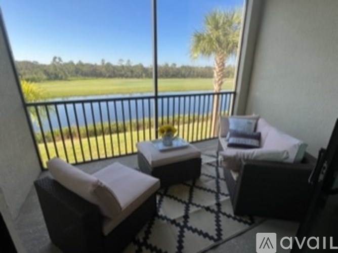 A balcony with two chairs and a table overlooking a body of water.