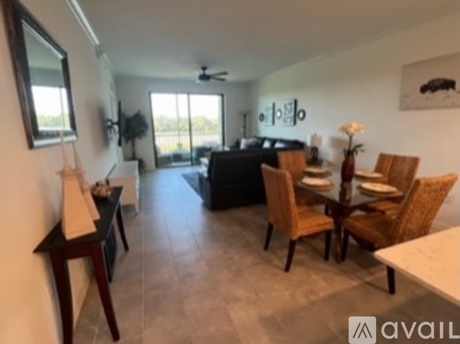 A living room with a black couch and wooden chairs.