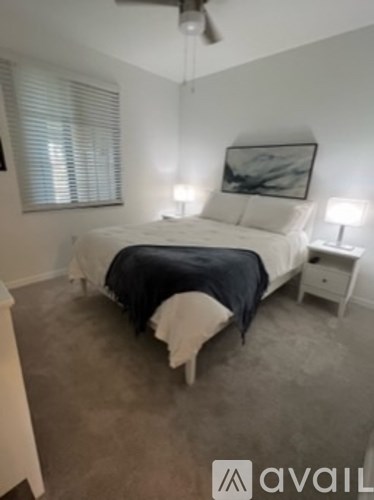 A bedroom with a bed, nightstand, and ceiling fan.