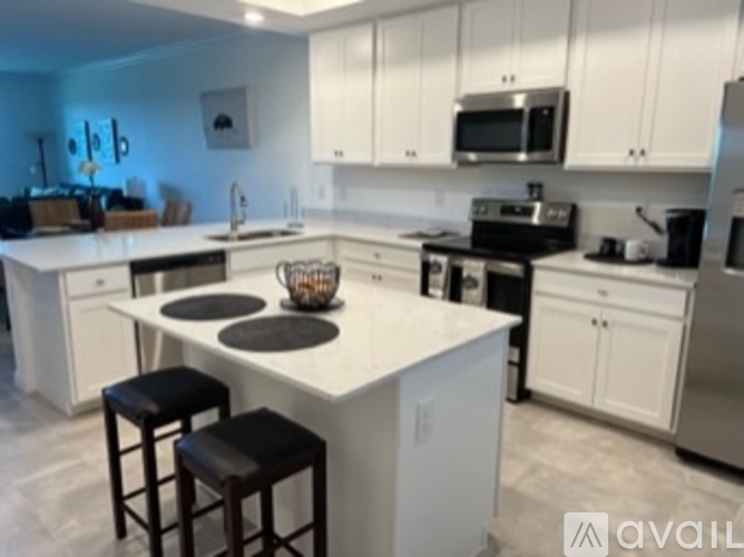A kitchen with white cabinets and a white island with a basket on it.
