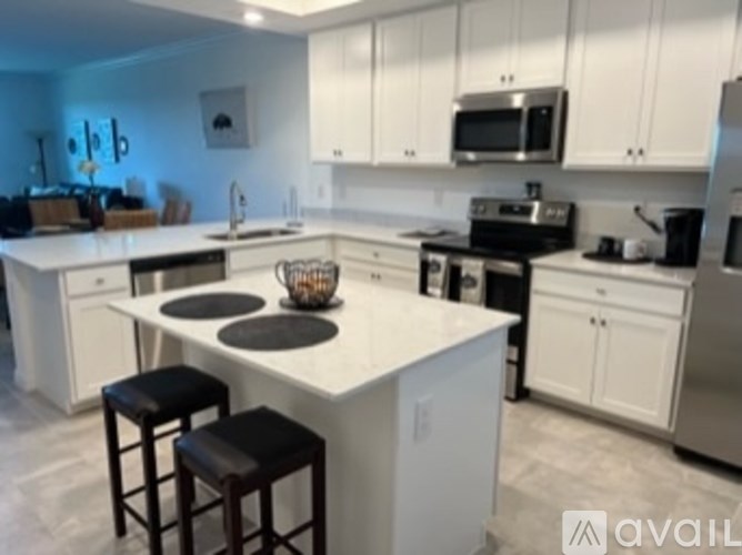 A kitchen with white cabinets and a white island with a basket on it.