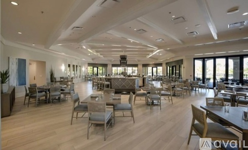 A spacious dining area with wooden floors and multiple tables.