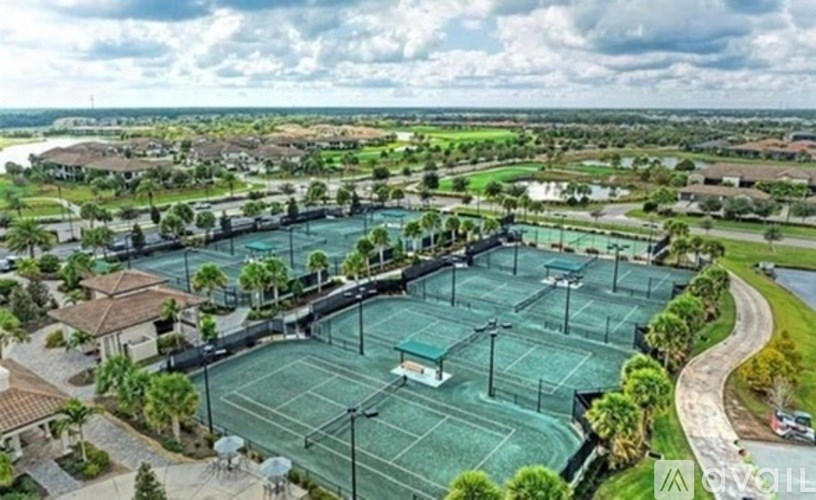 A tennis court surrounded by a green fence and trees.